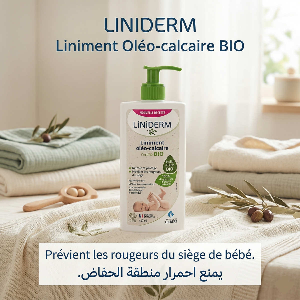 Flacon pompe de liniment oléo-calcaire bio Gilbert posé sur du linge de bébé, avec des olives
