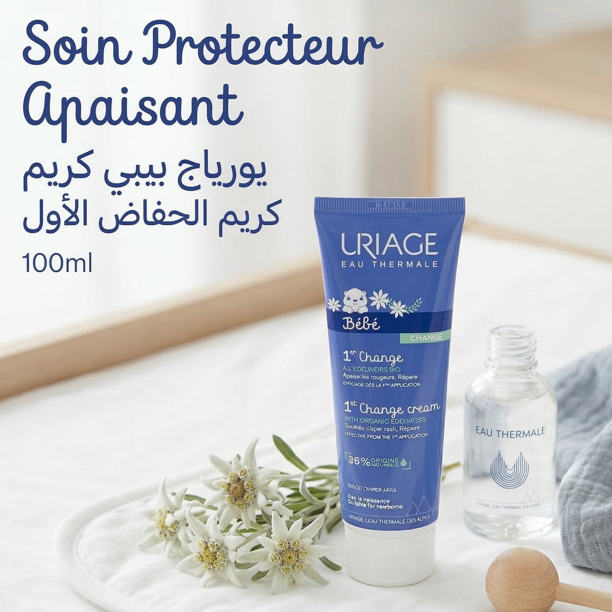Tube de crème Uriage Bébé 1er Change à l'edelweiss bio posé près de fleurs d'edelweiss et d'un flacon d'eau thermale