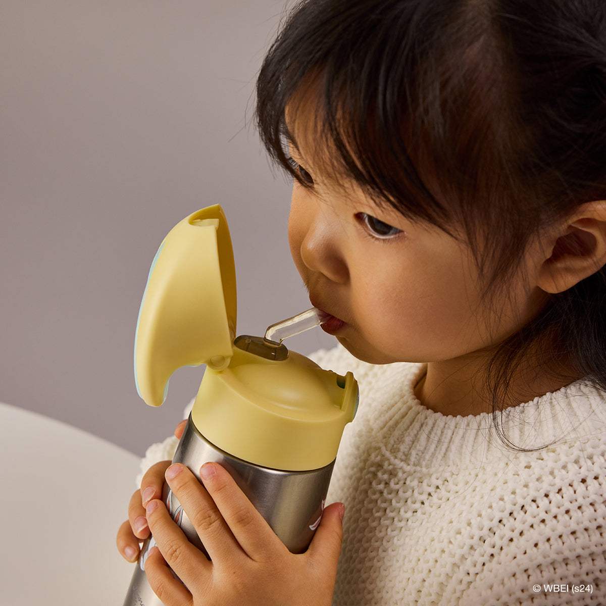 Fillette buvant à la paille de la gourde isotherme b.box Looney Tunes 350 ml, couvercle jaune ouvert